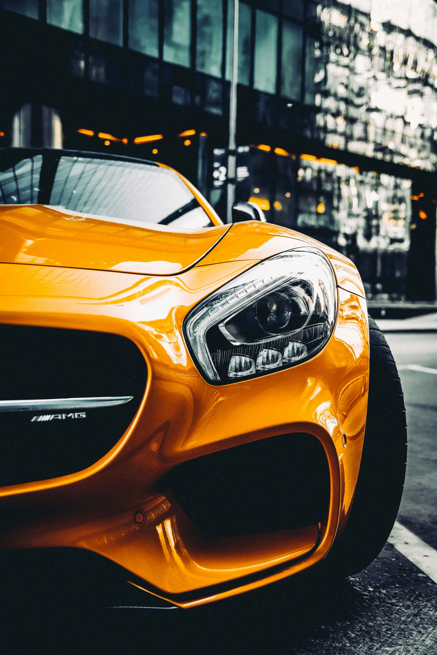 Pomarańczowe Mercedes-AMG GT z wypolerowanym lakierem na ulicy miasta